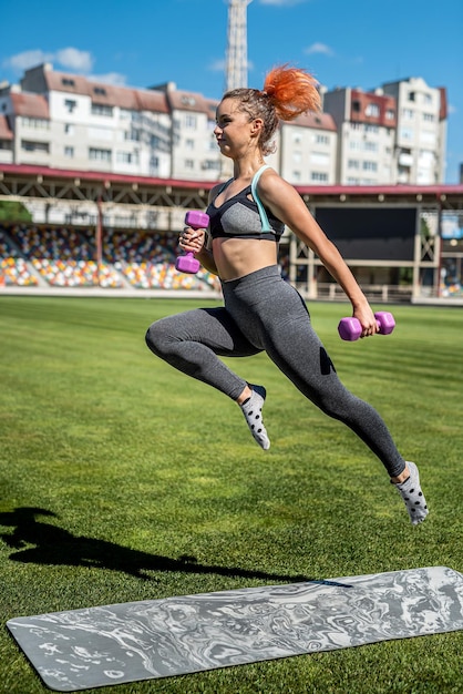 Treinadora atlética em roupas esportivas, fazendo exercícios de fitness no estádio verde