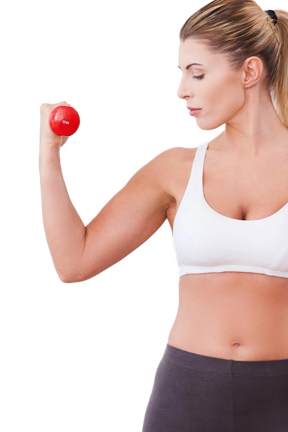 Treinamento com halteres. Linda mulher madura em roupas esportivas, treinando com halteres em pé, isolado no branco