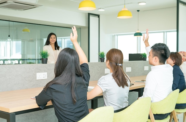 Treinamento da equipe de negócios em andamento com estagiários levantando as mãos para fazer perguntas