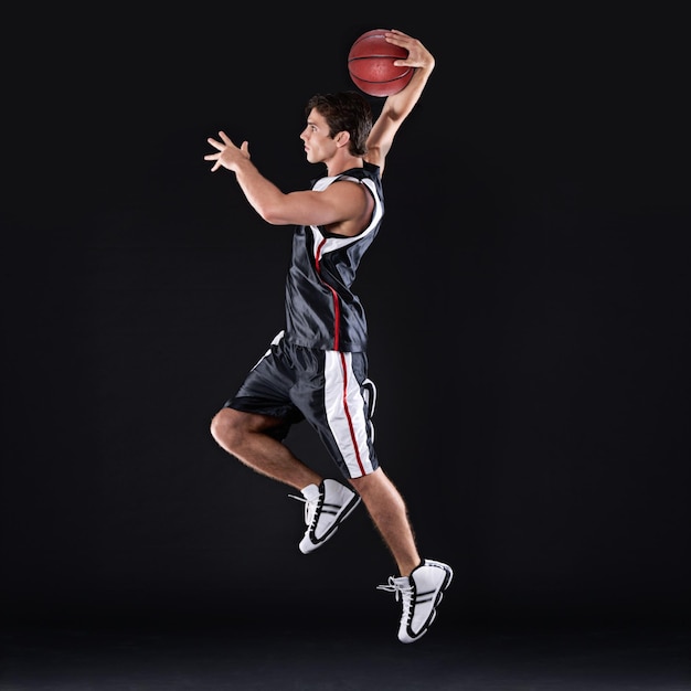 Treinamento de basquete e salto de homem em estúdio para exercício energia e aptidão corporal saudável Jogador de esportes e atleta atirando bola para jogo de competição e espaço de maquete isolado em fundo preto