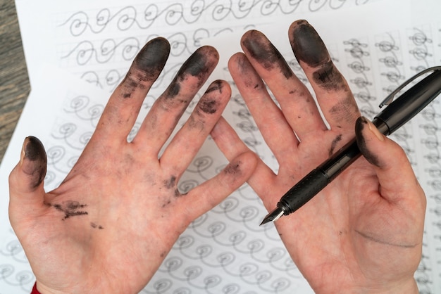 Treinamento de caligrafia. caneta-tinteiro nas mãos manchadas de tinta.