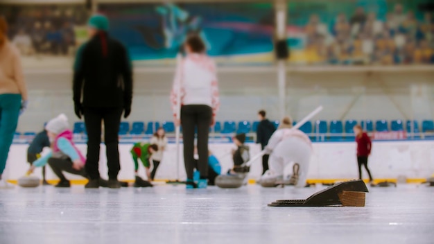 Treinamento de curling no complexo esportivo de diferentes pessoas treinando em segundo plano