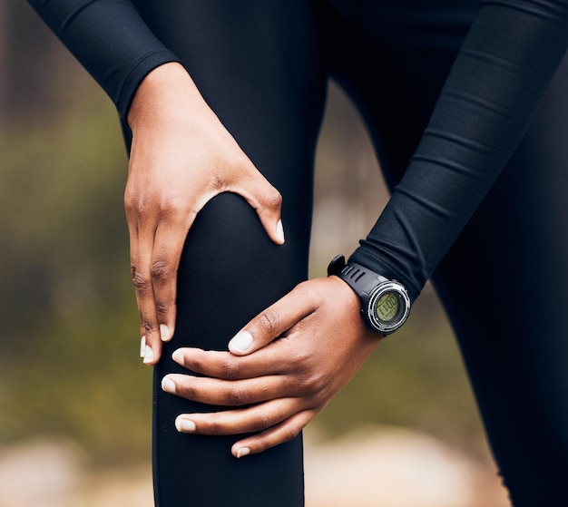 Foto treinamento de dor no joelho e pessoa correndo com lesão médica ou problema de anatomia esportiva na floresta ou na natureza exercício cardiovascular ou risco de treino de atleta corredor ou pessoas na floresta e zoom nas pernas