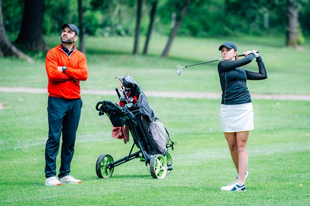 Treinamento de golfe Duas jovens com instrutor de golfe tendo uma aula em um campo de golfe