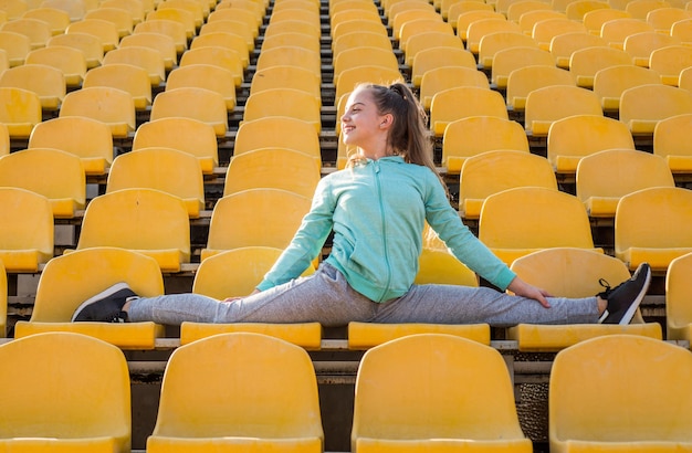 Treinamento de menina criança saudável dividido na pista de atletismo do estádio, esporte.