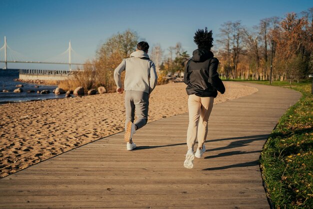 Treinamento físico Jogging ao longo do aterro na cidade Jovens amigos do casal praticam esportes