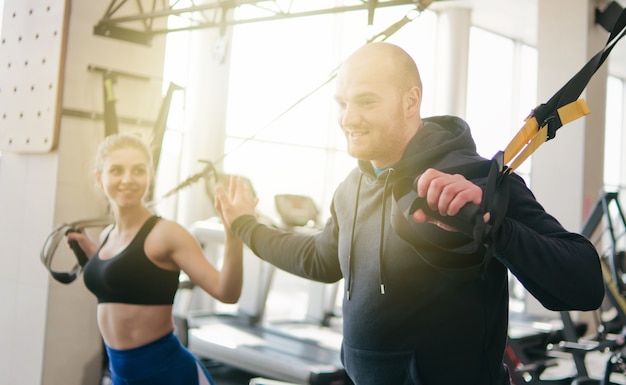 Treinamento funcional de casal. toca aqui. mulher e homem fazendo exercícios com alças de fitness no ginásio. treino funcional