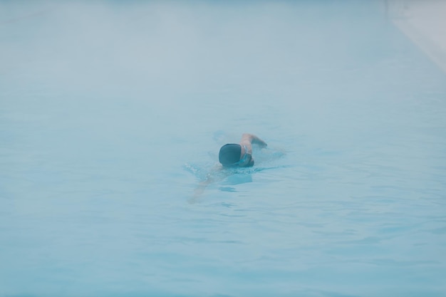 Treinamento masculino nadador apto nadar em piscina de inverno aberta com neblina Conceito de spa ao ar livre geotérmico