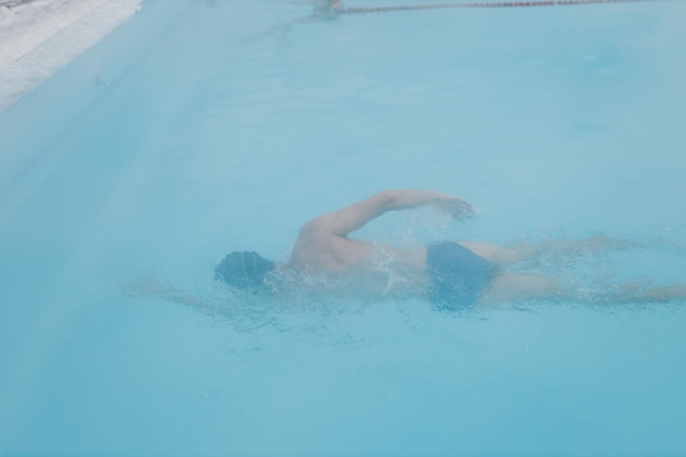 Treinamento masculino nadador apto nadar em piscina de inverno aberta com neblina Conceito de spa ao ar livre geotérmico