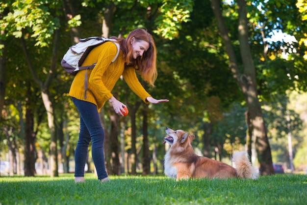 Treinamento - menina e cachorro corgi caminhando no parque