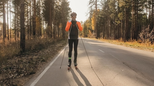 Foto treinando um atleta nos patinadores de patins passeio de biatlo nos esquis de patins com bastões de esqui