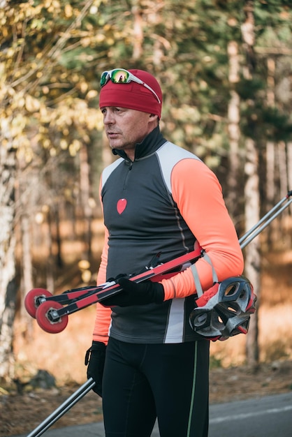 Foto treinando um atleta nos patinadores passeio de biatlo nos esquis com bastões de esqui no capacete treino de outono esporte de rolo o atleta vai e segura equipamentos esportivos na mão