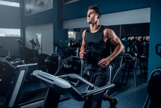 Foto treino de atleta masculino na máquina de exercícios em execução. treinamento esportivo ativo na academia