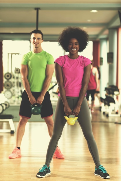 treino de casal saudável com pesos levantando halteres no ginásio crossfit mulher afro-americana com penteado afro