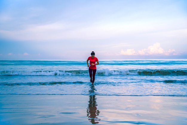 Treino de corrida garota correndo na praia de manhã.