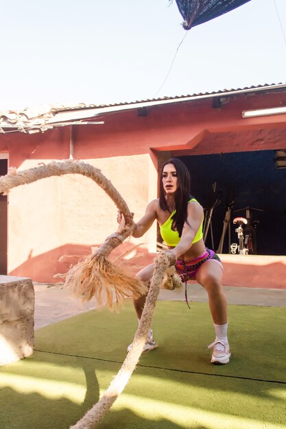 Treino de fitness de mulher com cordas de batalha no pátio do ginásio.