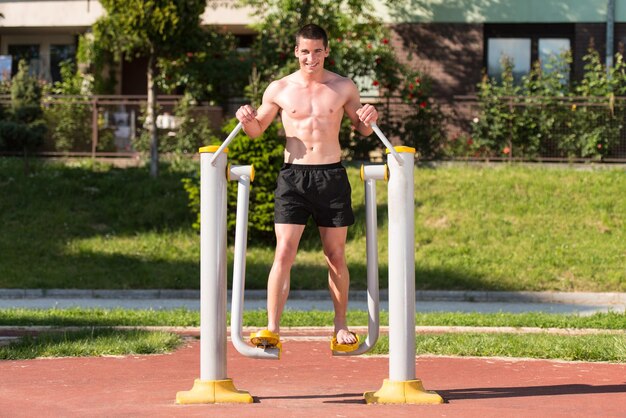 Treino de jovem musculoso bonito no parque