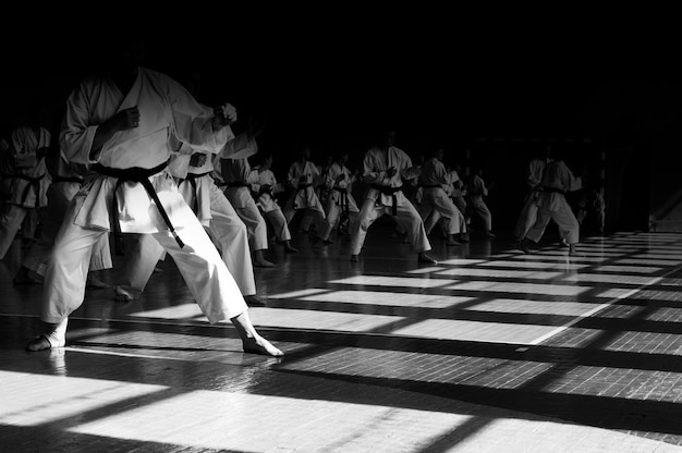 Treino de karatedo Imagem de fundo com espaço para texto Todos com a mesma forma e rostos escondidos no escuro O que torna as pessoas iguais irreconhecíveis Para páginas da web ou impressão de publicidade