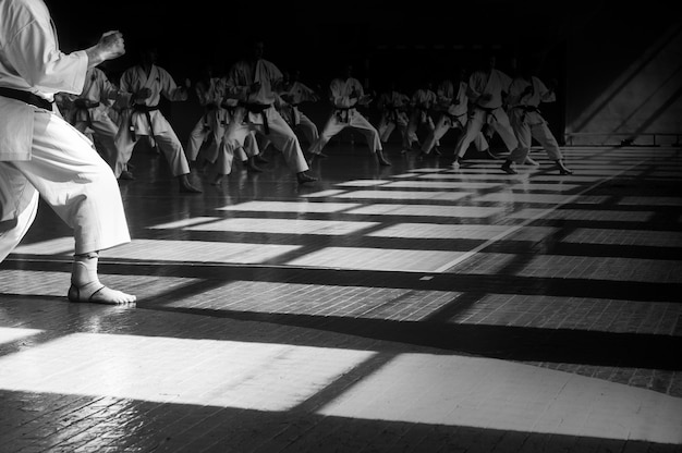 Treino de karatedo Imagem de fundo com espaço para texto Todos com a mesma forma e rostos escondidos no escuro O que torna as pessoas iguais irreconhecíveis Para páginas da web ou impressão de publicidade