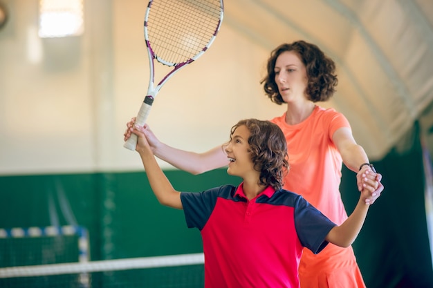 Treino de tênis. Adolescente de cabelos escuros treinando tênis com o treinador