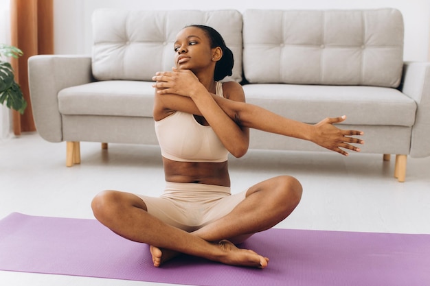 Foto treino doméstico. jovem negra desportiva fazendo exercício de prancha em casa, treinando na sala de estar