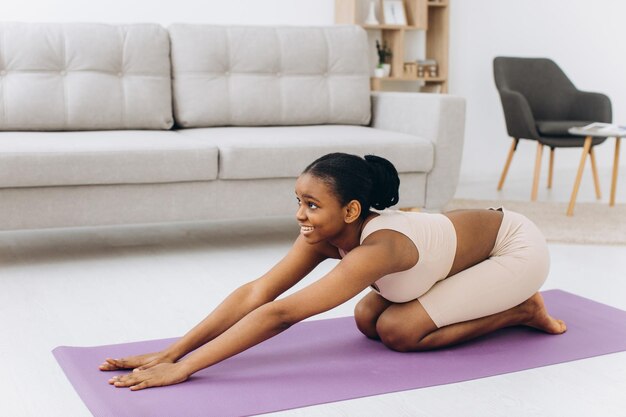 Treino doméstico jovem negra desportiva fazendo exercício de prancha em casa treinando na sala de estar