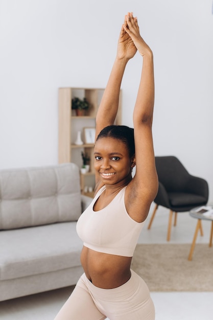 Treino doméstico jovem negra desportiva fazendo exercício de prancha em casa treinando na sala de estar