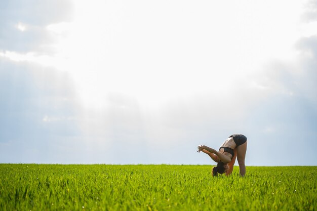 Treino matinal. conceito de estilo de vida saudável. jovem mulher atraente em roupas esportivas faz esticar a mão antes de treinar na natureza ao amanhecer. aquecimento muscular