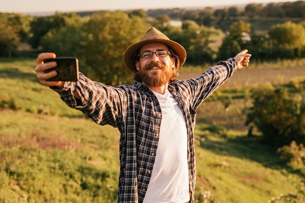 Foto trekker hippie masculino tirando selfie com smartphone para blog de viagens