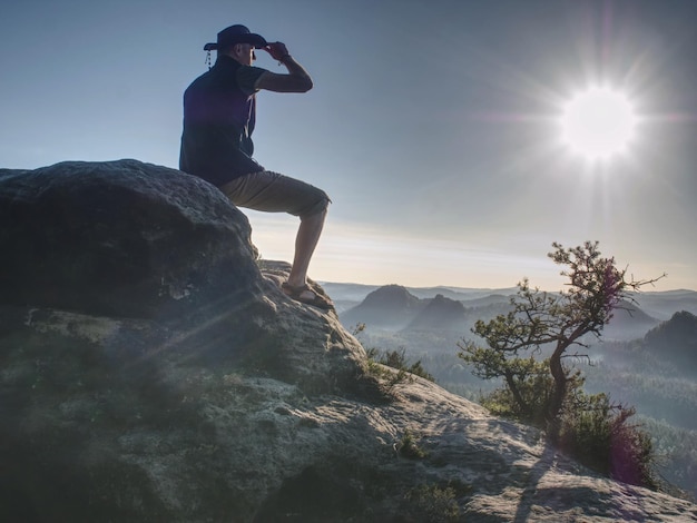 Foto trekker in cowboy-hut genießt die aussicht auf den berg mit wunderschönem sonnenaufgang und nebel im morgengebirge