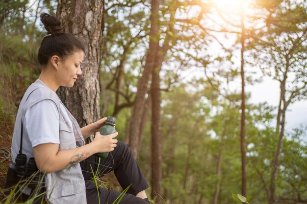 Trekking-Konzept Frau trinkt Wasser im FreienErfrischung beim Wandern im WaldFemale Tourist Resting