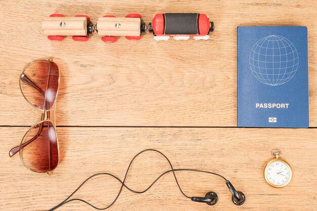 Trem de madeira, fones de ouvido, passaporte e outros atributos do viajante na velha mesa de madeira como pano de fundo