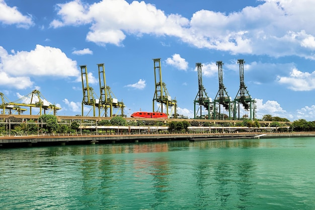 Trem expresso de passageiros e guindastes de carga na ilha de Sentosa, em Cingapura. Terminal de contêineres portuários ao fundo