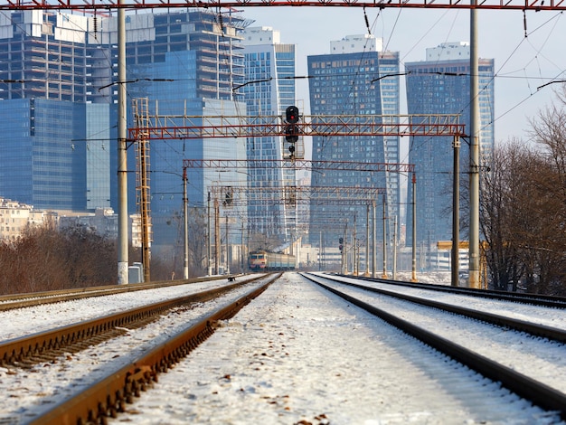 Foto el tren eléctrico se mueve por los rieles contra el telón de fondo de un paisaje urbano de invierno