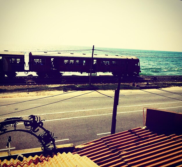 Tren en medio de la carretera y el mar contra un cielo despejado