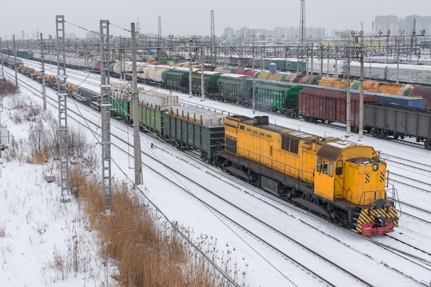 Tren de mercancías al patio de clasificación en invierno en la nieve. Locomotora amarilla.