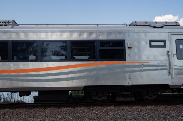 El tren nacional pasa por la vía férrea cuando es de día con el cielo azul