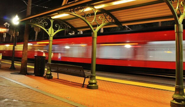 Foto tren que sale de una estación de tren iluminada por la noche