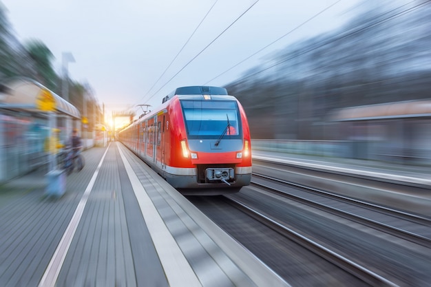 Tren rojo de alta velocidad del pasajero con el desenfoque de movimiento en la estación.