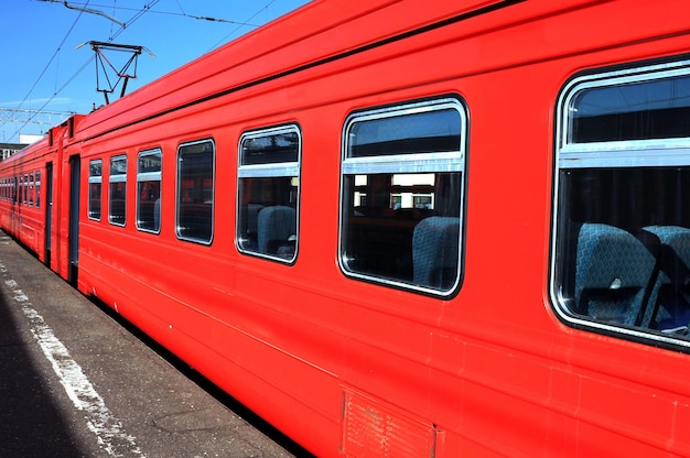 Un tren rojo está estacionado junto a una línea eléctrica.