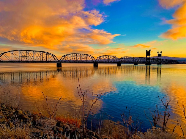 Foto tren tressel en las tres ciudades del estado de washington reflejo sobre el río columbia al atardecer