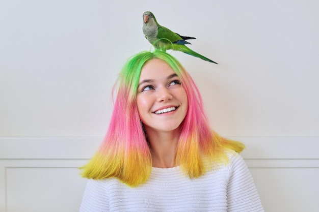 Trendig modisch mit farbiger Frisur Teenager mit grünem Papagei auf dem Kopf