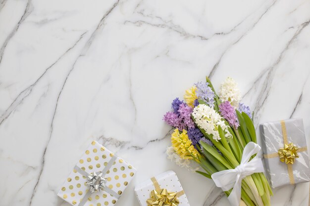 Trendige Komposition der Draufsicht mit festlich verpackter Bandschleife der Geschenkboxen, verziert durch Blütenblumen