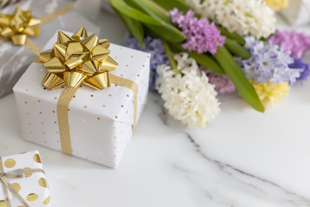 Trendige Komposition mit festlich verpackten Geschenkboxen, die von Blütenblumen verziert werden