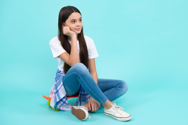 Trendige schöne Teenager-Model posiert auf blauem Studiohintergrund Kind Mädchen in T-Shirt und Jeans Studioaufnahme Teen Mode Glücklicher Teenager positive und lächelnde Emotionen von Teenager-Mädchen