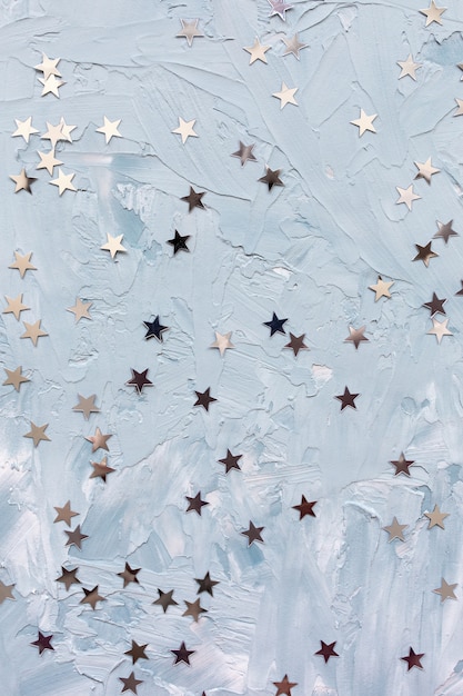 Trendige Silberfolienkonfetti-Sterne auf weißem und blauem Hintergrund. Abstrakter Hintergrund des Winters. Weihnachtsfeier, Feiertage und Träume Konzept