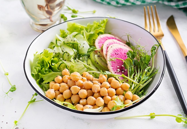 Trendiger salat. vegane buddha-schale mit kichererbsen, wassermelonenrettich, gurke und erbsensprossen. gesunde ausgewogene ernährung.