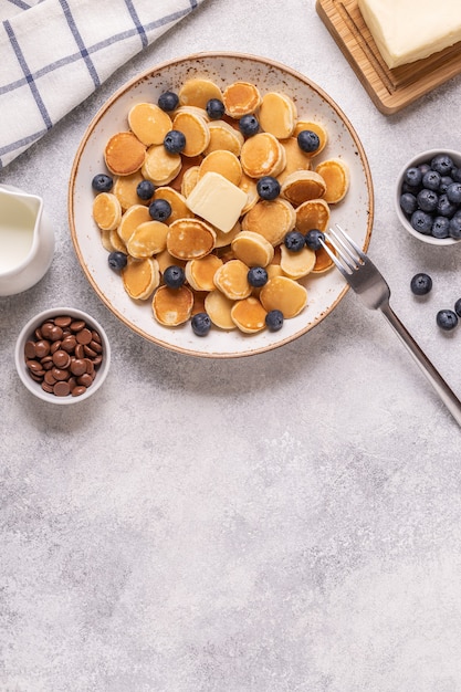 Trendiges Frühstück mit Mini-Pfannkuchen und Blaubeeren, Draufsicht.