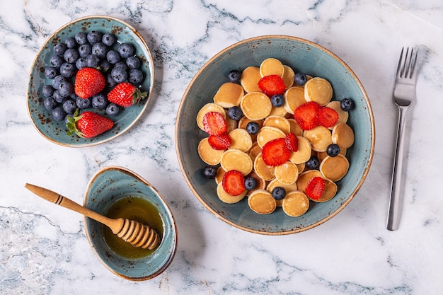 Trendiges Frühstück mit Minipfannkuchen, Blaubeeren und Erdbeeren, Draufsicht.