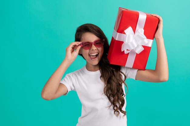 Trendiges Kind bereitet sich auf den Urlaub vor. fröhlichen Valentinstag. Shopping-Finale ausverkauft. jugendlicher Käufer. Teenager-Mädchen mit Sonnenbrille halten Geschenkbox. Einkaufszeit. glückliches Kind hält Geschenk.